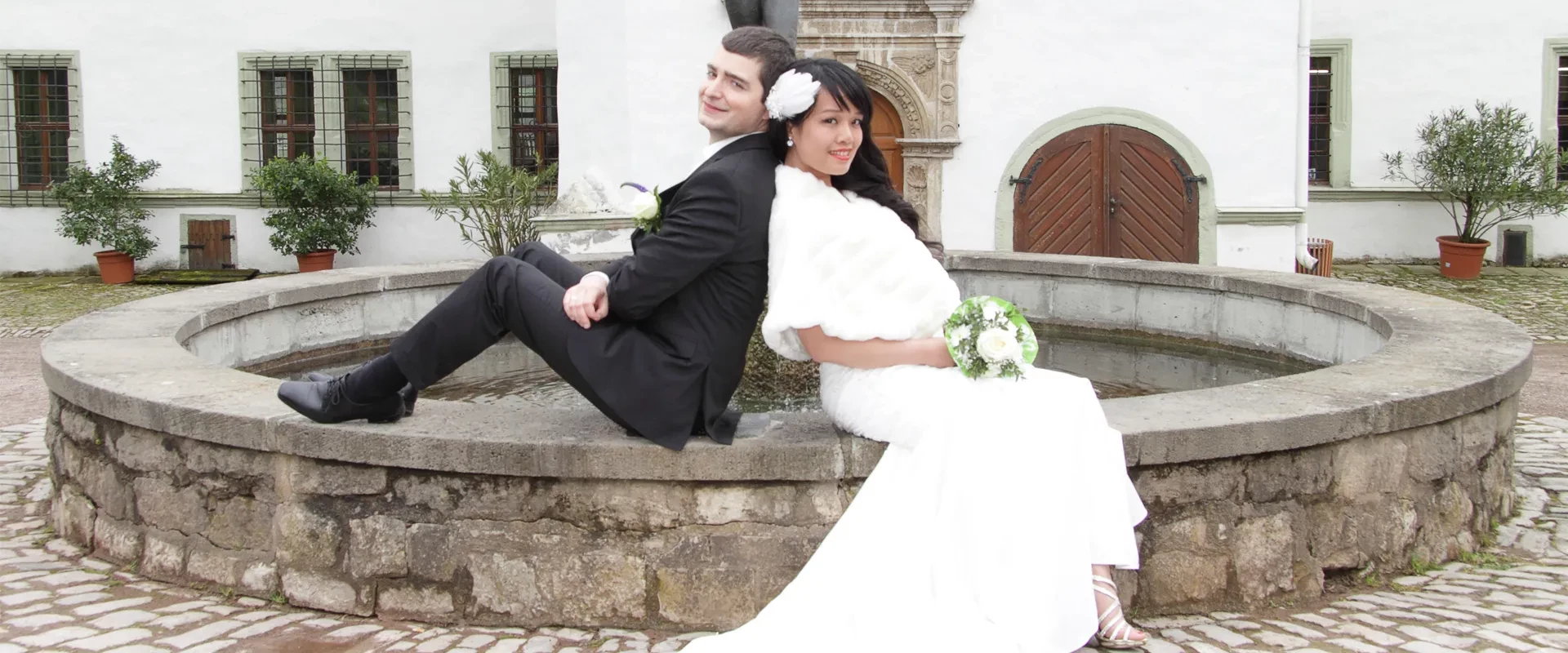 Hochzeitsbild eines jungen Paares am Brunnen eines Schlosses